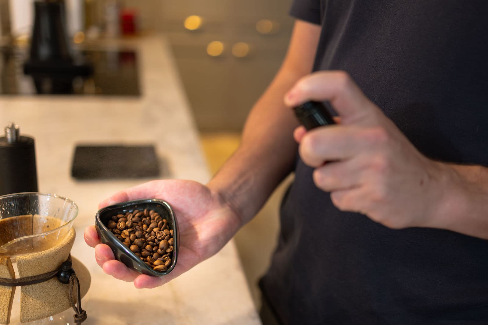 Grãos torrados do Café Nepré na mão, ao lado de um coador com café passando